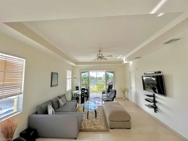 Open-concept living area with tray ceilings and crown molding
