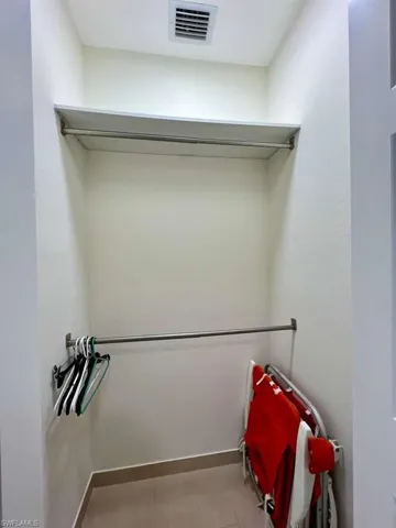 Closet with built-in shelving, dual hanging rods, and tile flooring