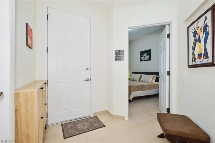 Entryway featuring light-toned tile flooring and a paneled white door with a polished chrome handle