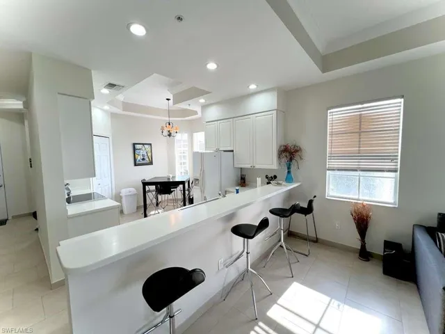 Open-concept kitchen and dining area featuring a breakfast bar, white cabinetry, recessed lighting, and tile flooring