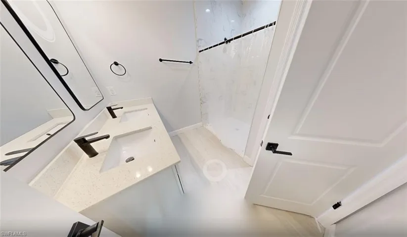 Bathroom with double vanity and a marble finish shower