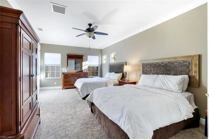 Bedroom featuring light carpet, ornamental molding, and a ceiling fan