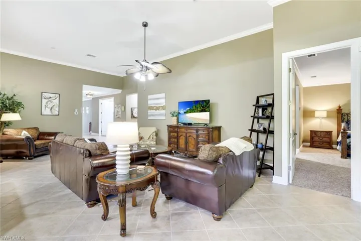 Living room featuring ornamental molding, light tile patterned floors, and a ceiling fan