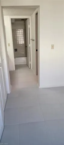 Kitchen with brown cabinetry, light tile patterned floors, light countertops, under cabinet range hood, and stainless steel appliances