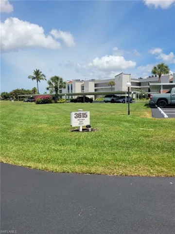 View of front of house featuring covered and uncovered parking and a front yard