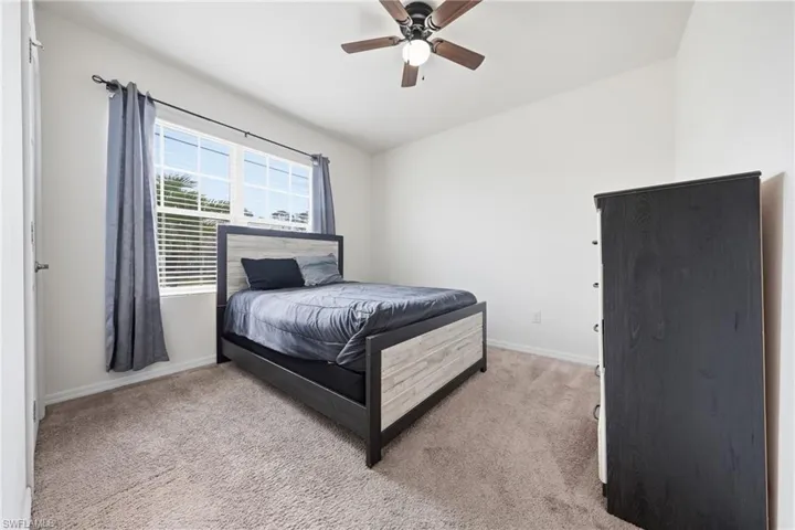 Bedroom with light carpet, lofted ceiling, and ceiling fan