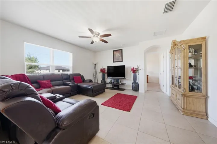 Living room featuring arched walkways, a ceiling fan, and light tile patterned flooring