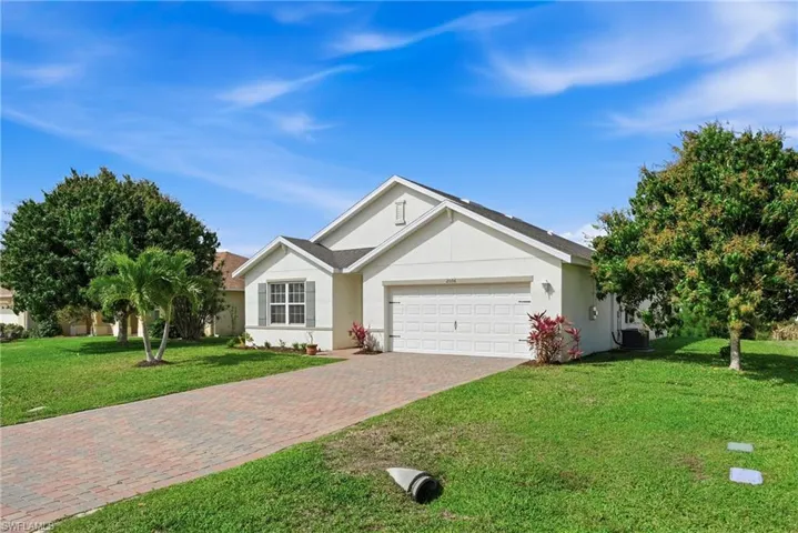 Ranch-style home with a front lawn, a garage, decorative driveway, and stucco siding