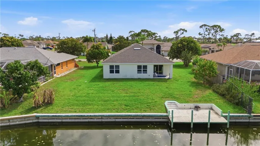 Back of property featuring a residential view, a water view, a patio area, a lawn, and stucco siding