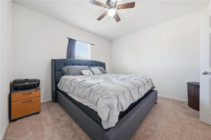 Bedroom with ceiling fan and light carpet