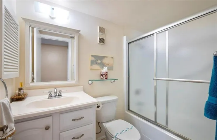 Bathroom featuring a vanity with a white countertop and sink, a mirrored medicine cabinet, and a shower with frosted glass sliding doors