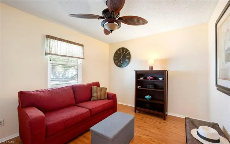 The room features a window with blinds, a ceiling fan, and light-toned walls