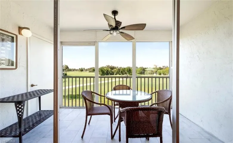 Screened lanai featuring a ceiling fan, a tiled floor, and views of a golf course and a body of water