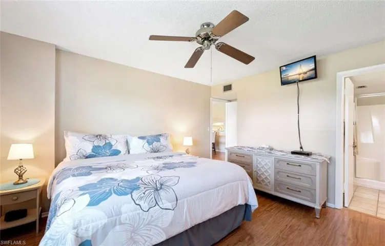 The room features wood-style flooring, a ceiling fan, and access to a bathroom with a bathtub