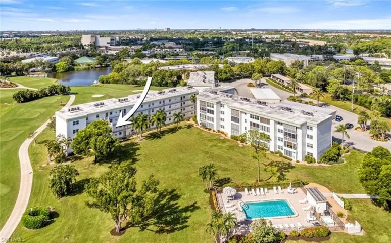 The property features a building with multiple levels overlooking a green landscape with mature trees and a paved path