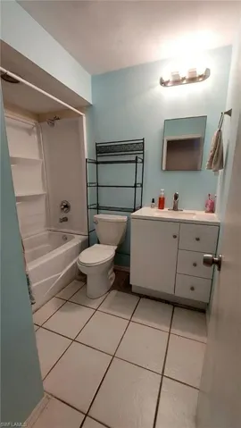 Full bathroom with shower / washtub combination, toilet, tile patterned flooring, and vanity