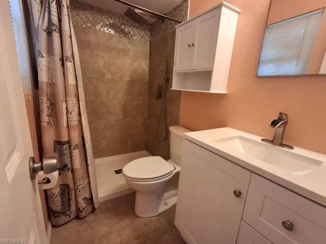 Bathroom with a shower with shower curtain, vanity, and toilet