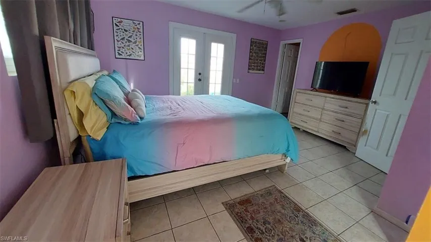 Tiled bedroom featuring french doors and ceiling fan