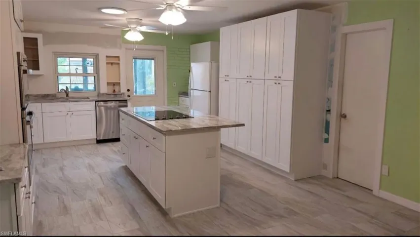 Kitchen featuring stainless steel dishwasher, white refrigerator, white cabinets, and a kitchen island
