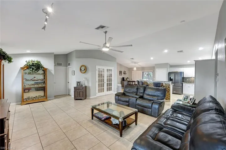 Living area with a ceiling fan, baseboards, vaulted ceiling, light tile patterned floors, and recessed lighting