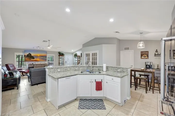 Kitchen featuring dishwasher, a sink, vaulted ceiling, ceiling fan, and white cabinets