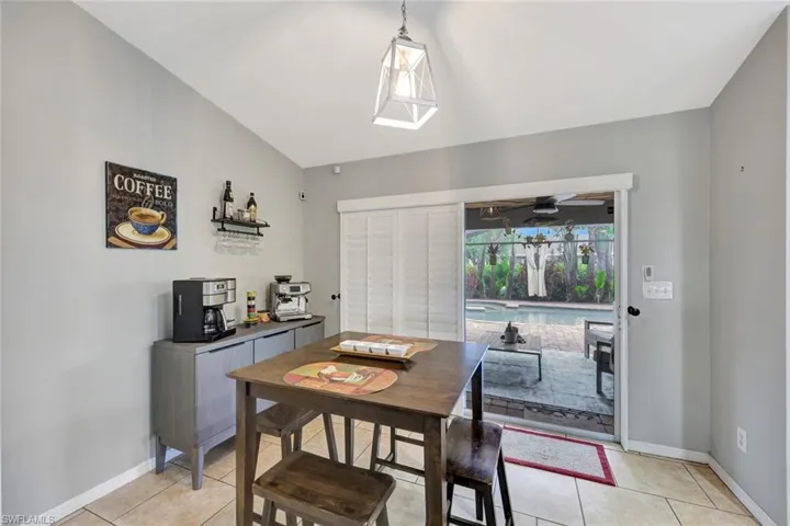 Dining room featuring light tile patterned floors, baseboards, lofted ceiling, and ceiling fan