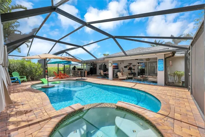View of pool featuring a patio area, a pool with connected hot tub, a ceiling fan, and a lanai