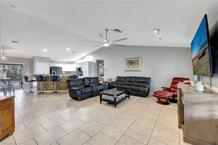 Living area with a ceiling fan, vaulted ceiling, light tile patterned floors, recessed lighting, and baseboards