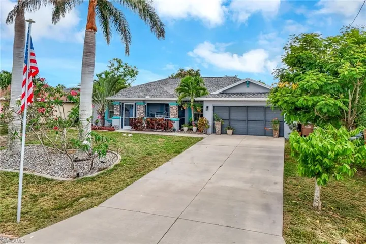 Single story home featuring an attached garage, concrete driveway, a front lawn, roof with shingles, and a porch