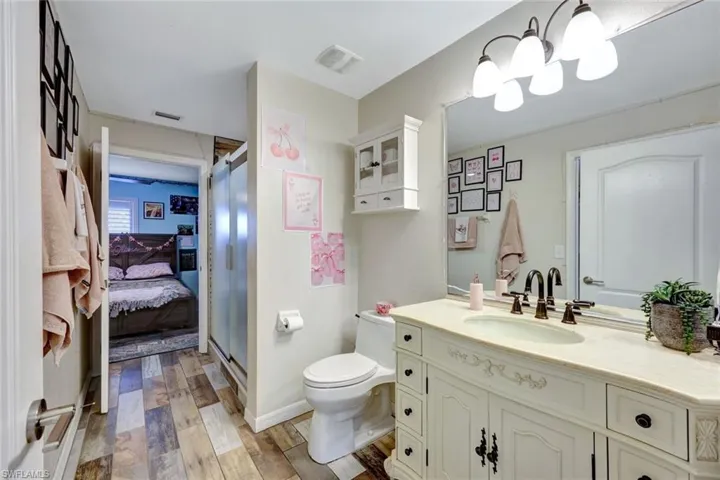Full bath with vanity, wood finished floors, toilet, and a shower with door