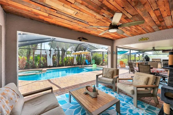 View of pool with a ceiling fan, a patio area, glass enclosure, a pool with connected hot tub, and area for grilling