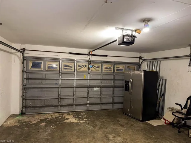 Garage featuring stainless steel fridge and a garage door opener