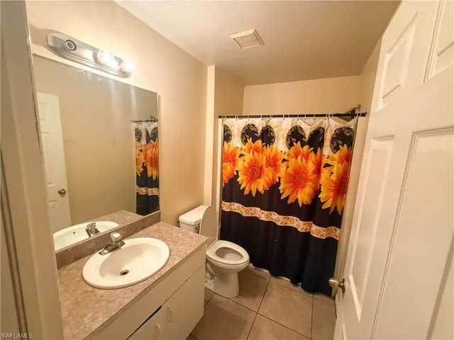 Bathroom with vanity, light tile patterned floors, and curtained shower