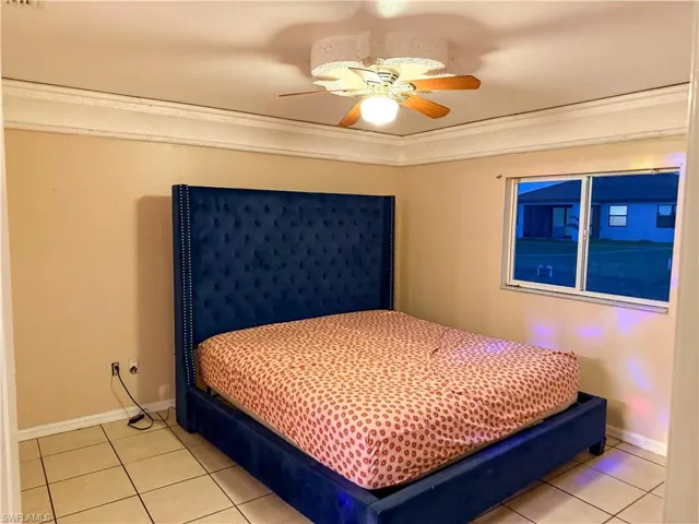 Bedroom featuring a ceiling fan, ornamental molding, and light tile patterned floors