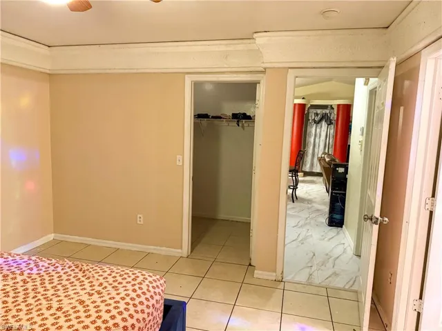 Bedroom with light tile patterned flooring and a walk in closet