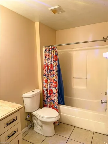 Bathroom featuring vanity, light tile patterned floors, and shower / bath combination with curtain