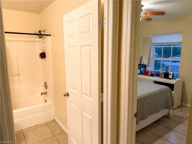 Bathroom featuring light tile patterned flooring, bathing tub / shower combination, and ceiling fan