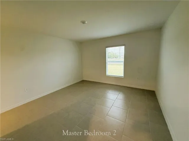 Empty room featuring baseboards and light tile patterned floors