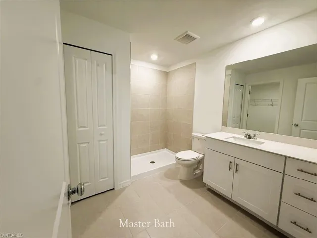 Full bathroom featuring vanity, light tile patterned floors, a shower stall, recessed lighting, and a walk in closet