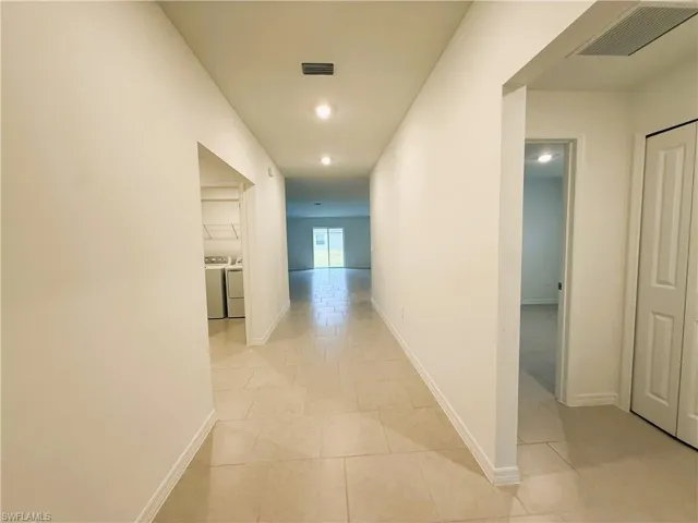 Hallway with independent washer and dryer, light tile patterned flooring, and recessed lighting