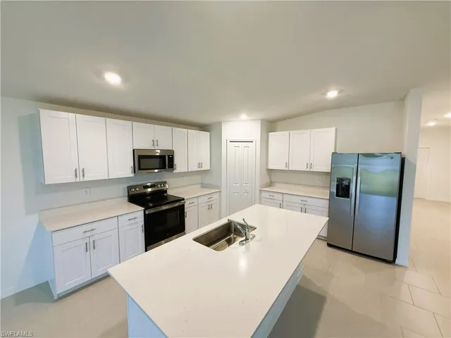 Kitchen featuring stainless steel appliances, white cabinetry, a center island with sink, and recessed lighting