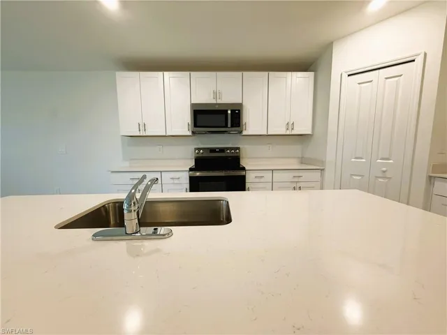 Kitchen with white cabinetry, stainless steel appliances, light stone countertops, and recessed lighting