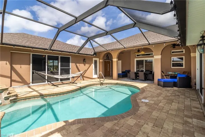 Pool with outdoor lounge area, a patio area, ceiling fan, and glass enclosure