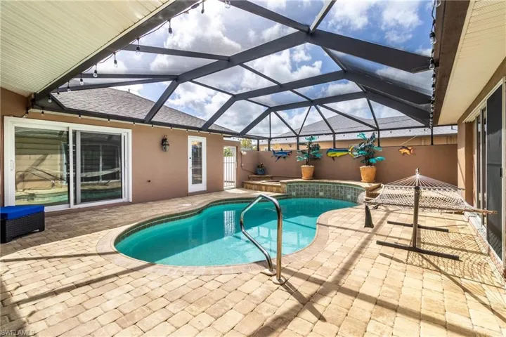 Outdoor pool featuring a patio area, an in ground hot tub, and glass enclosure
