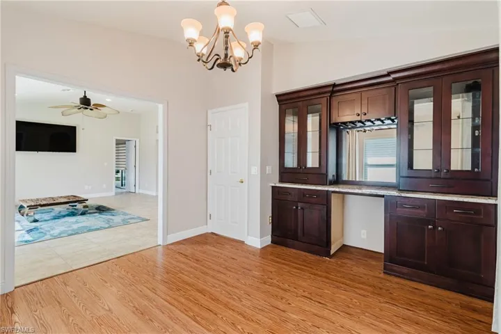 Kitchen featuring light wood-type flooring, glass insert cabinets, lofted ceiling, and dark brown cabinetry