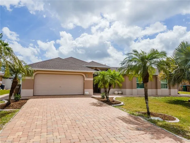 View of front of property with a front yard, an attached garage, decorative driveway, and stucco siding