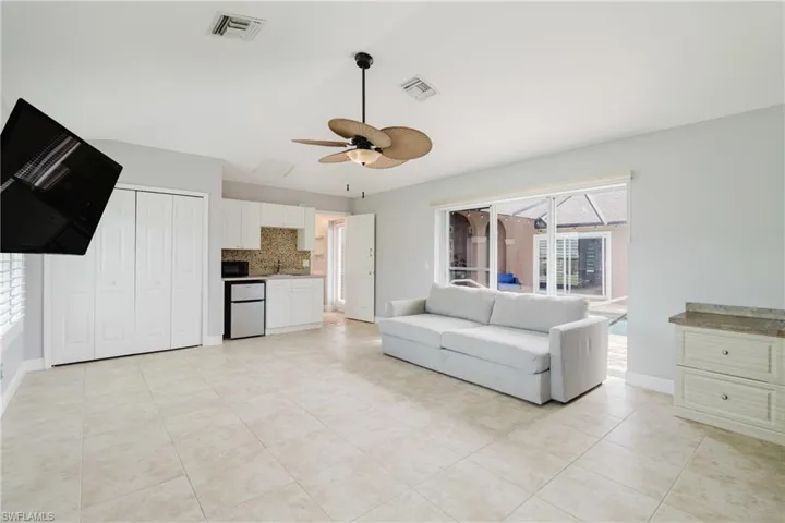 Unfurnished living room featuring a sink, visible vents, ceiling fan, and baseboards