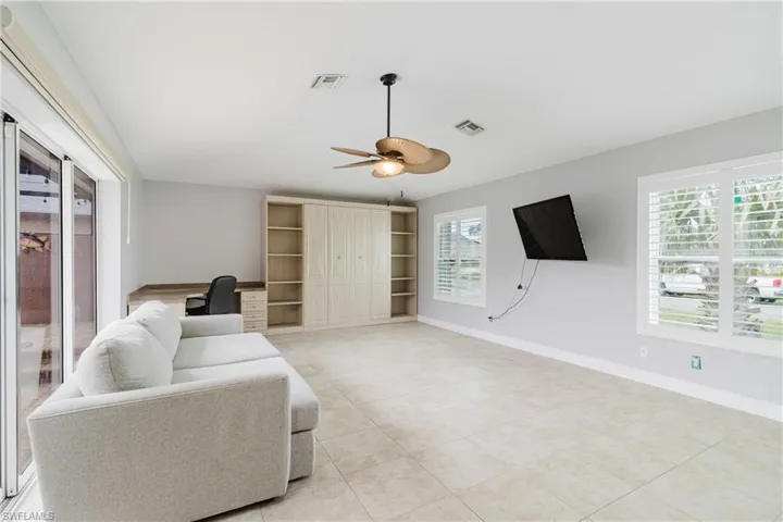 Living room featuring visible vents, baseboards, a ceiling fan, and light tile patterned floors