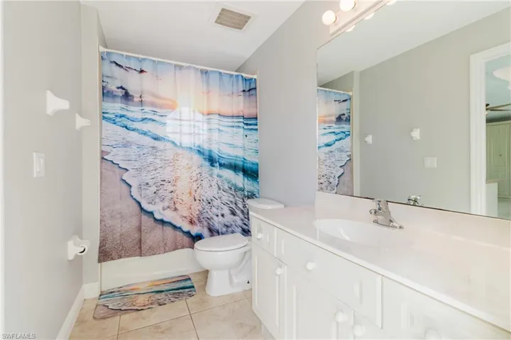 Bathroom featuring a shower with shower curtain, vanity, tile patterned flooring, toilet, and visible vents