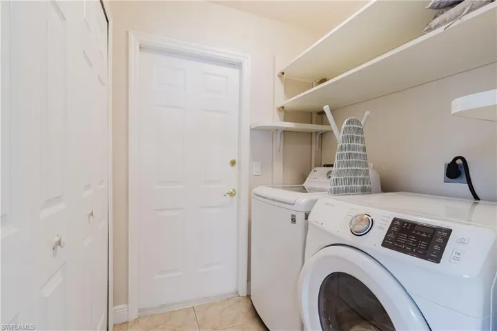 Clothes washing area with light tile patterned floors, laundry area, and washing machine and clothes dryer